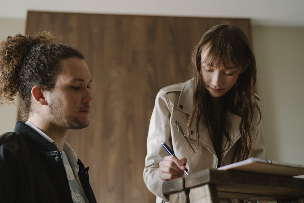 A young couple reviews and signs real estate documents indoors.